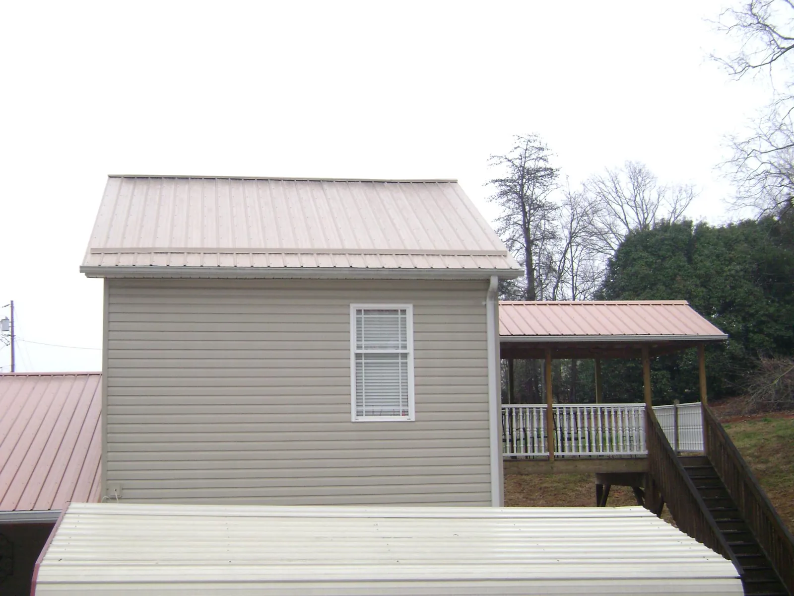 Tan metal roofs on a two story addition and attached porch, from a Roof Replacement job in Julian