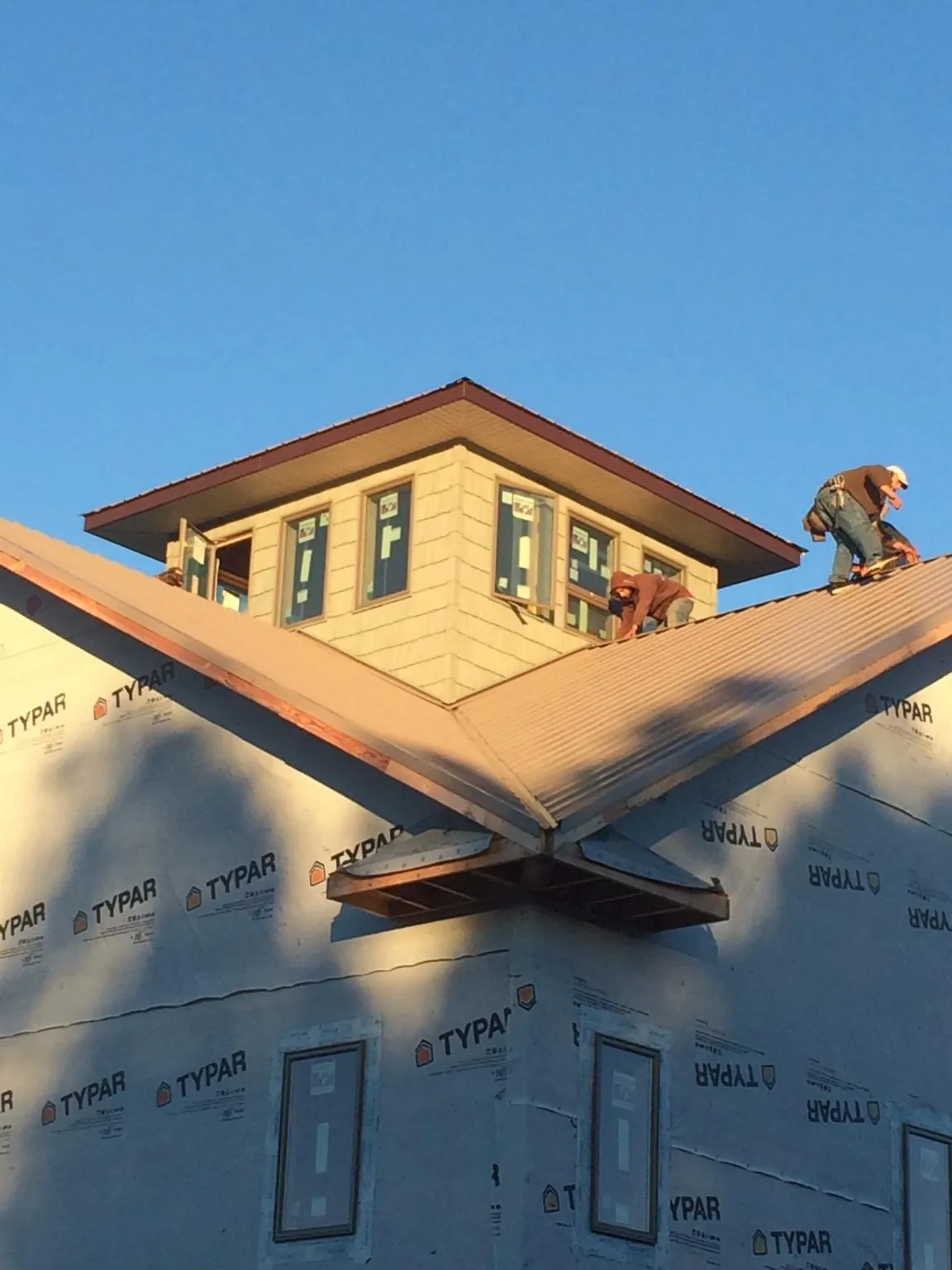 Roofers working around a rooftop cupola on a new metal roof at sunset — Roof Waterproofing in Julian by Roofing Brothers